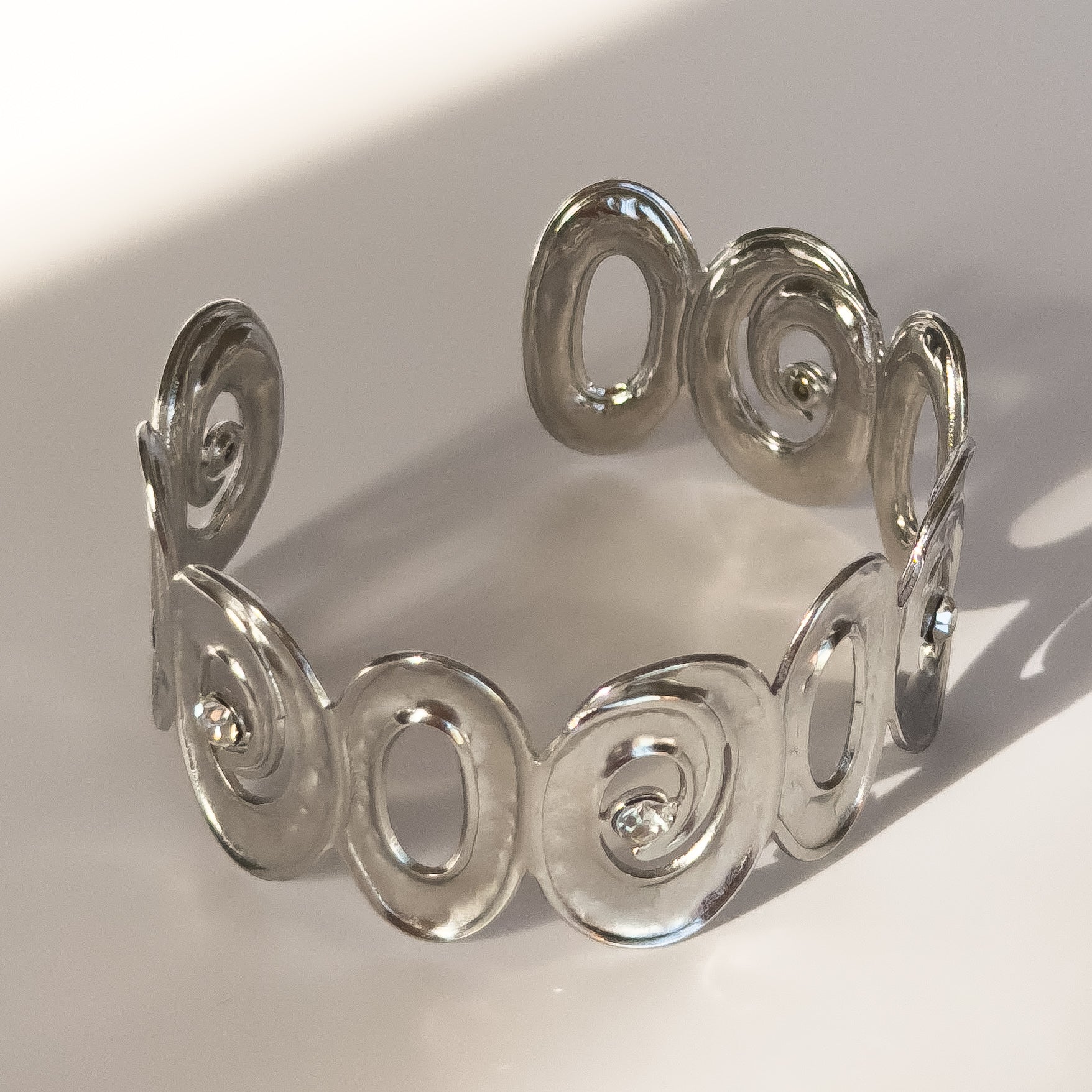 Silver bracelet with circular design on a light background