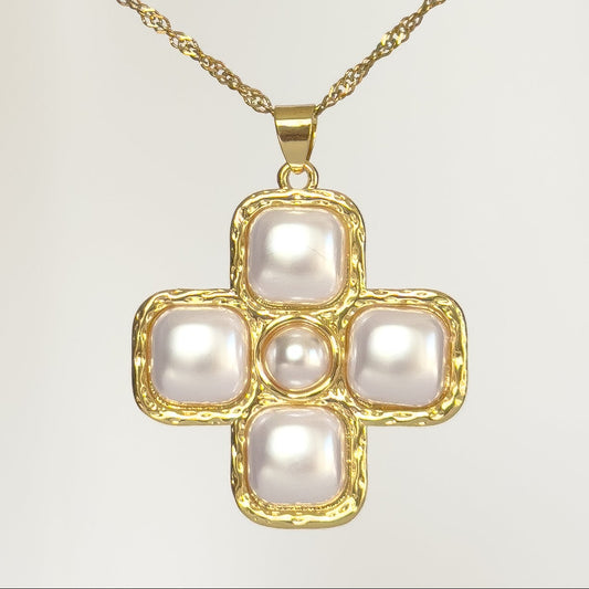 Gold cross-shaped pendant with pearls on a light gray background